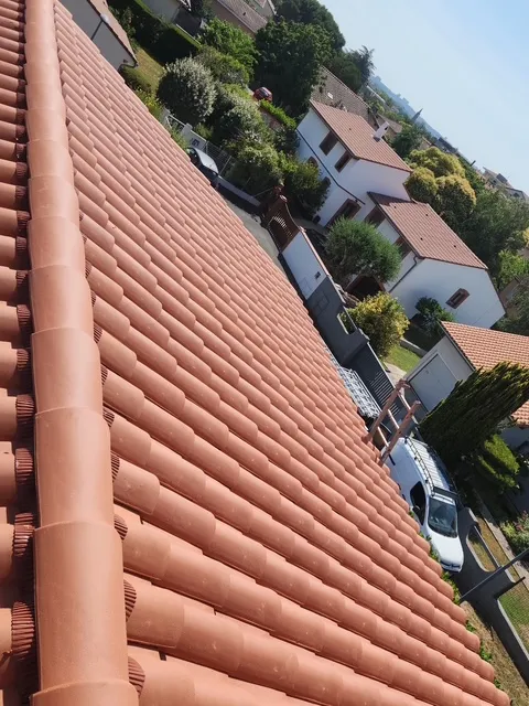 Toiture achevée en tuiles de terre cuite avec faîtage assorti, vue depuis le versant